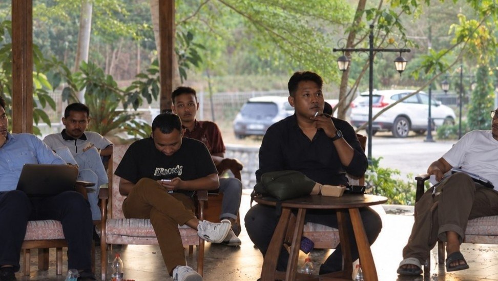 Sejumlah warga duduk dalam sebuah pertemuan komunitas di ruang terbuka
