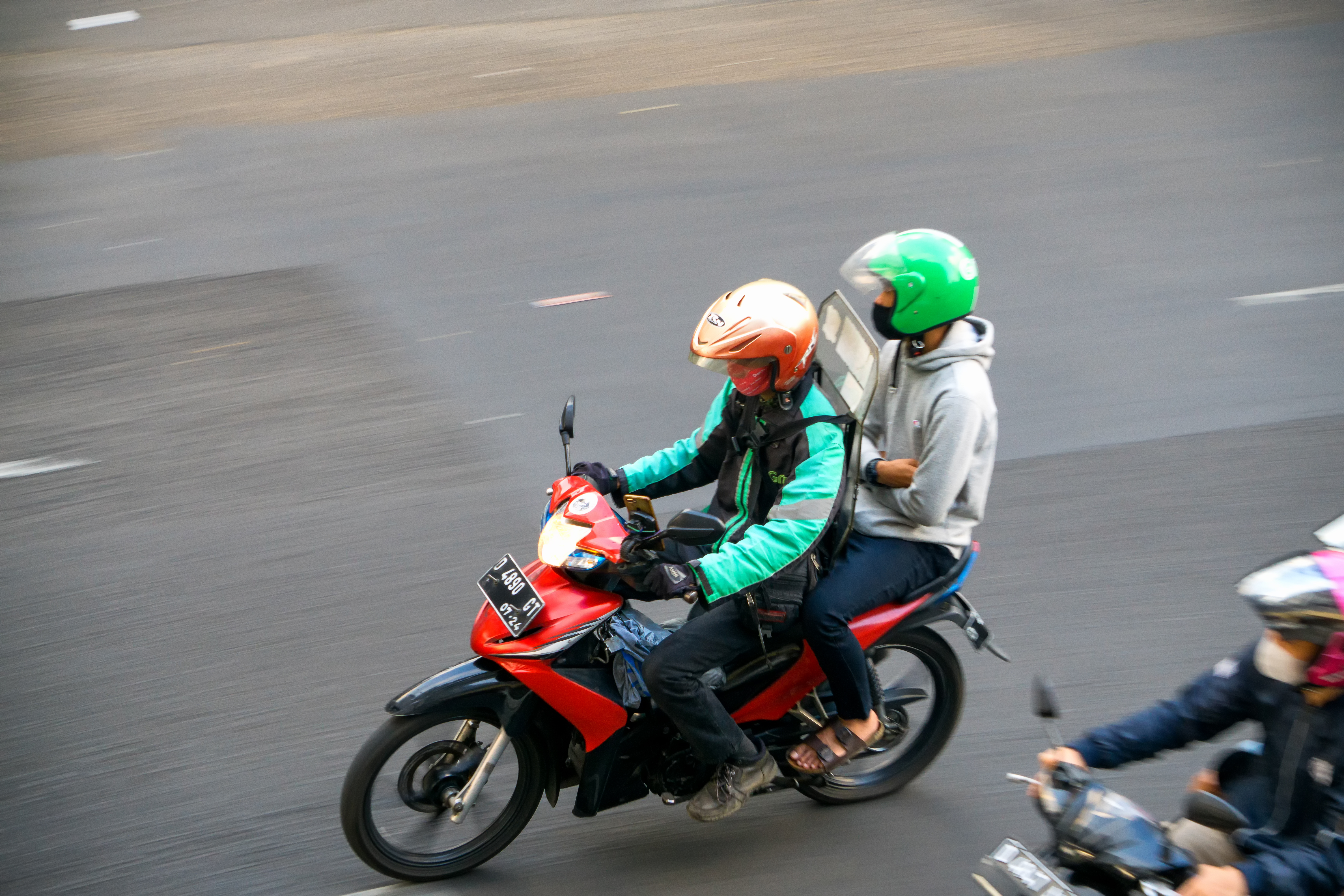 Pengemudi ojek online membawa penumpang di jalan raya Indonesia