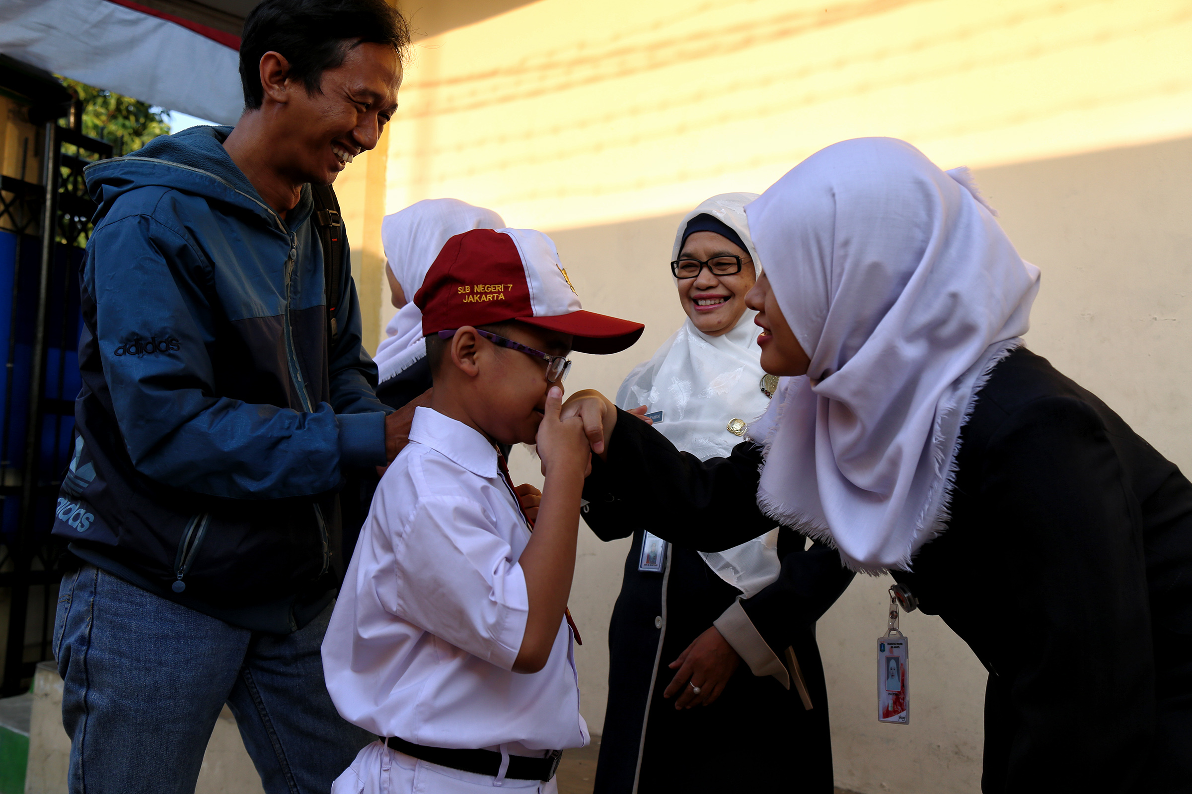 Guru menyambut siswa di lingkungan sekolah di Indonesia